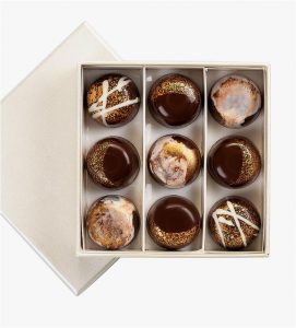 A box of nine chocolate covered cookies in it.