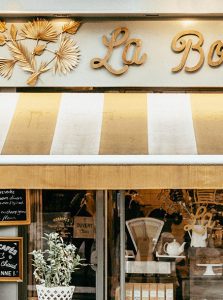 A store front with many signs and flowers on the windows.