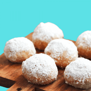 A wooden board with powdered donuts on top of it.