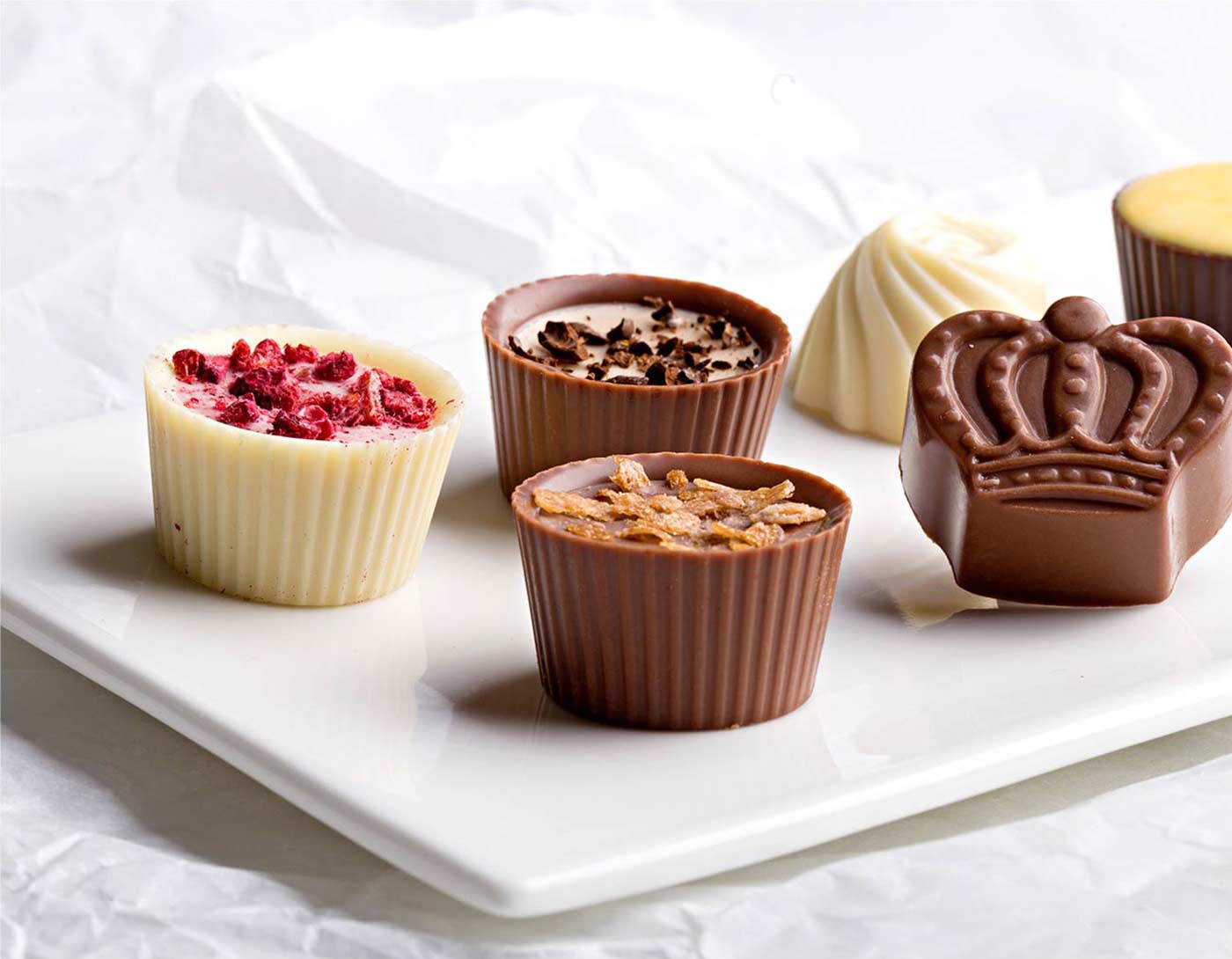 A white plate topped with chocolate cups and candies.