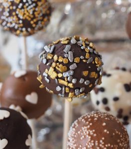A close up of several cake pops on sticks