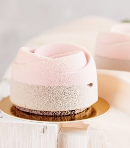 A small cake with pink frosting on top of it.