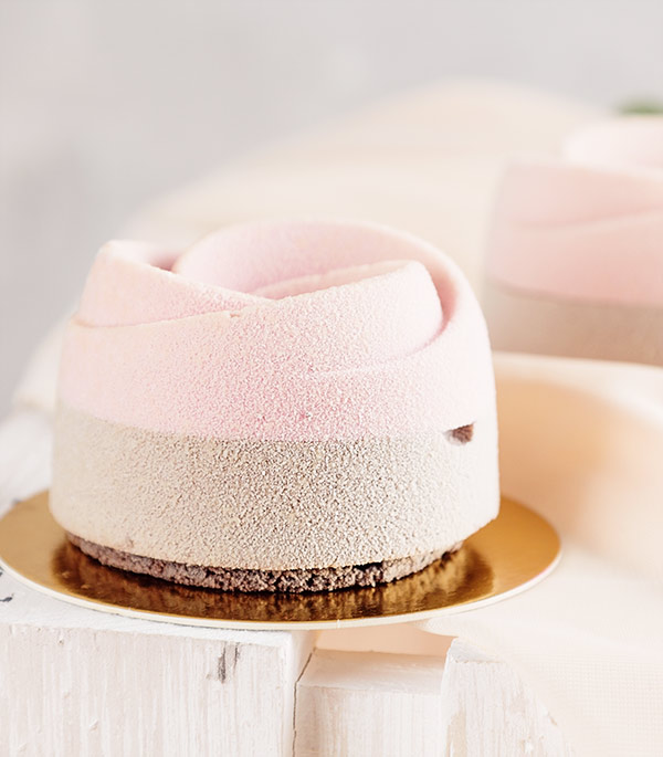 A small cake with pink frosting on top of it.