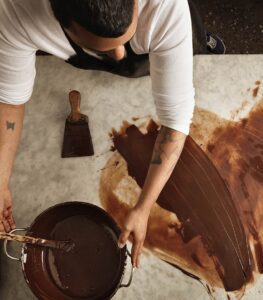 Person spreading chocolate on a marble surface.