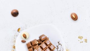 A white plate topped with chocolate covered nuts.
