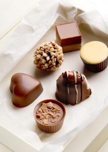 A tray of chocolates on top of white paper.