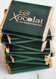 A stack of chocolate boxes with the logo xocolat on them.