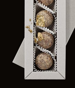 Three chocolate balls in a box with gold foil.