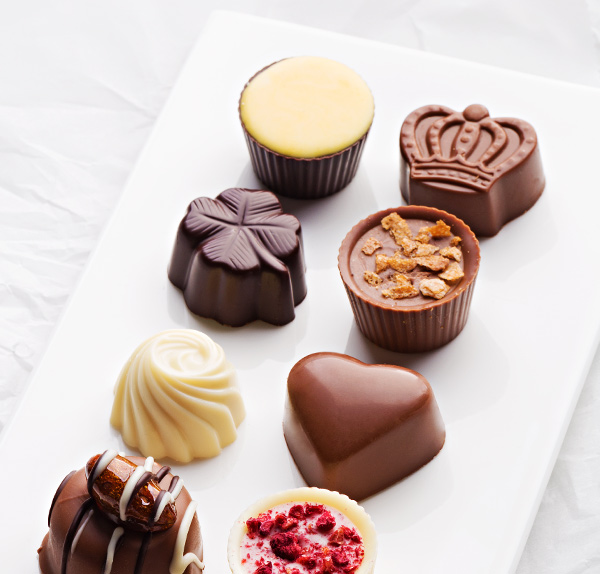 A white plate topped with lots of different chocolates.
