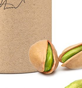 A bag of pistachios with one pistachio in the background.