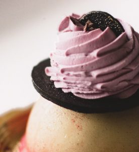 A close up of some pink frosting on top of a cake.