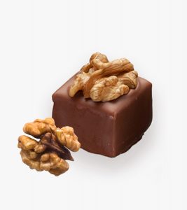 A square chocolate box with nuts on top of it.