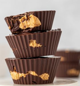 Three chocolate cups with peanut butter on top of each other.