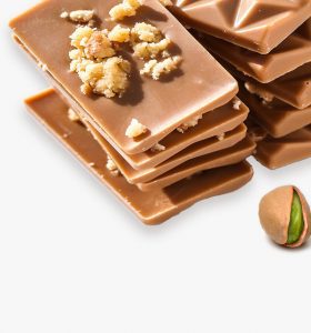 A pile of chocolate covered nuts next to a pistachio.