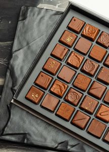 A box of chocolates with different designs on them.
