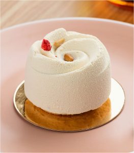 A small white cake on top of a pink plate.