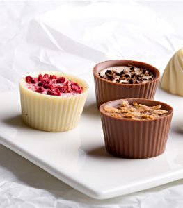 A white plate topped with three cups of food.