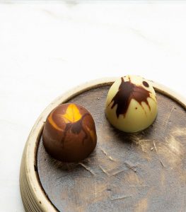 Two chocolate candies on a wooden plate