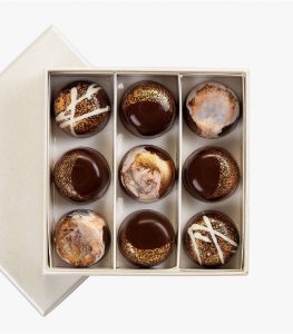 A box of nine chocolate covered cookies in it.
