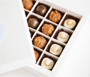 A box of chocolates with one opened to reveal the contents.
