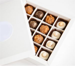 A box of chocolates with one opened to reveal the contents.