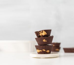 A stack of chocolate peanut butter cups on top of a white plate.