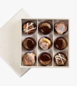 A box of nine chocolate covered cookies in a white box.