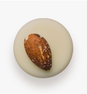 A white candle with an almond on top of it.