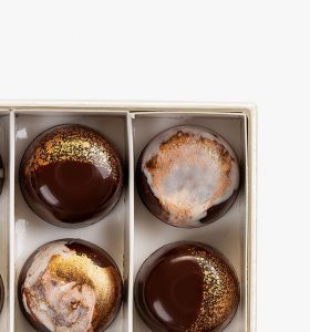 A box of chocolate covered cookies with gold leaf.