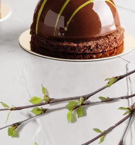 A cake with chocolate frosting on top of a white plate.