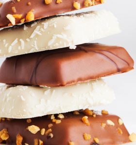 A stack of chocolate covered cookies with nuts.