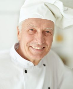 A man in chef 's outfit smiling for the camera.