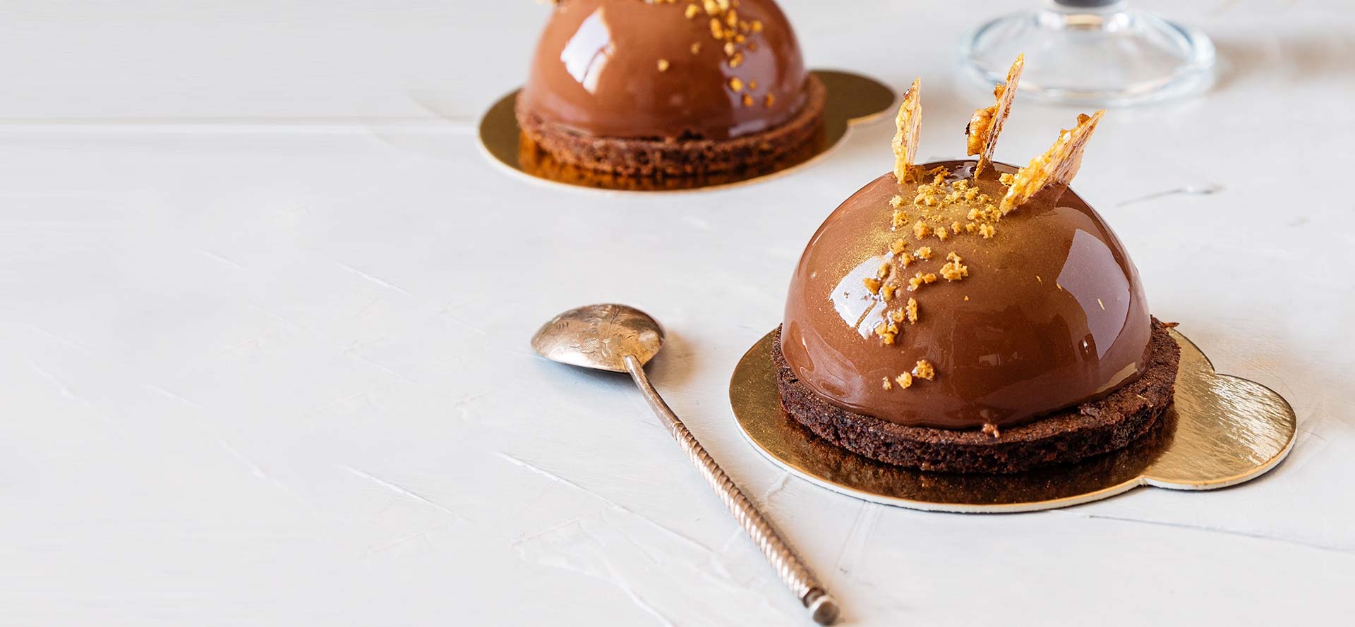 A spoon and two cakes on plates
