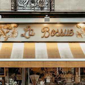 A store front with the name of a restaurant in gold letters.