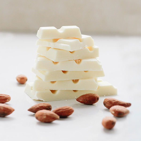 A stack of white chocolate bars next to almonds.