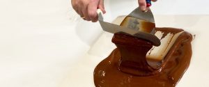 A person is cutting chocolate on top of a table.