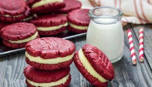 A table with some red velvet cookies and milk