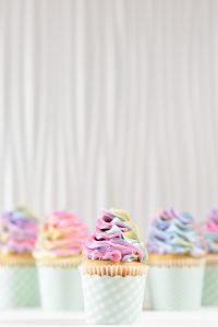 A row of cupcakes with different colored frosting.