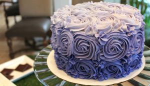A purple cake with roses on top of it.