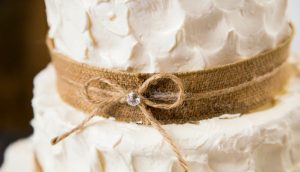 A close up of the burlap ribbon on top of a cake.