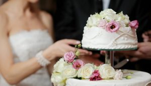 A couple is holding their wedding cake