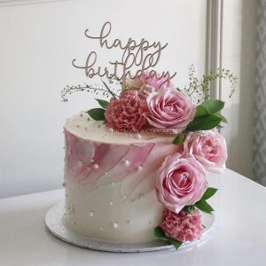 A birthday cake with pink flowers and white frosting.