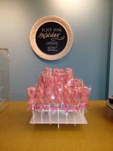 A table with pink ribbon lollipops on it