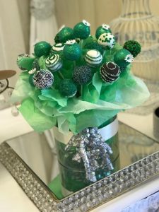 A bouquet of green cake pops in a glass vase.