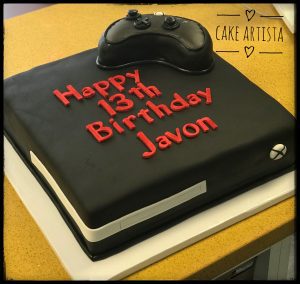 A black cake with a controller on top of it.