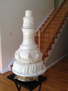 A large white cake on top of a wooden floor.