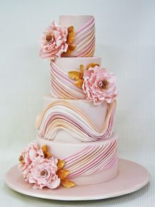 A pink and white cake with flowers on top of it.