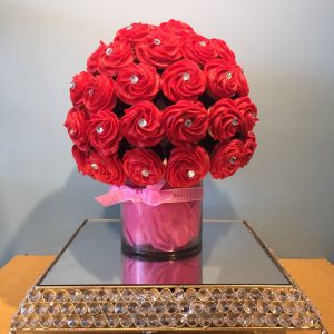 A red rose bouquet in a pink vase on top of a table.