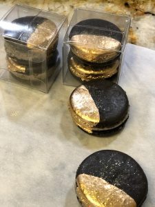 A table with several black and gold cookies on it.