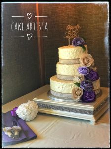 A three tiered cake with purple flowers on top of it.
